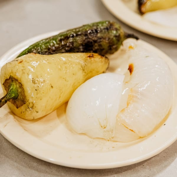 Grilled green and yellow peppers with sliced white onions on a light plate.